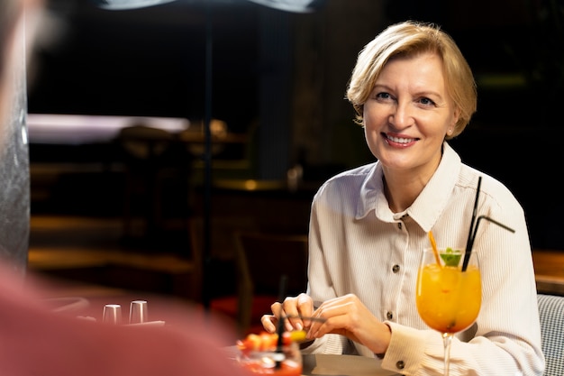 Free photo senior woman eating at a restaurant with friends