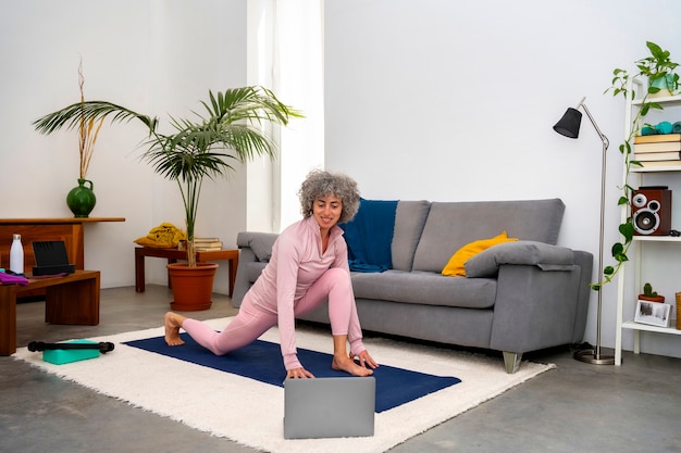 Free photo senior woman exercising indoors full shot