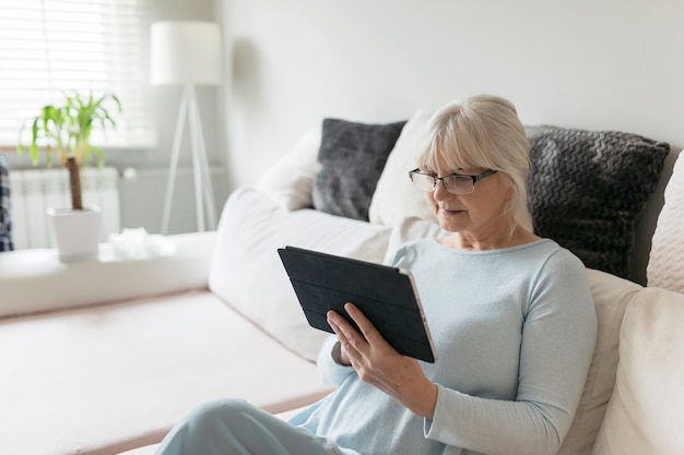 Senior woman in glasses browsing tablet 