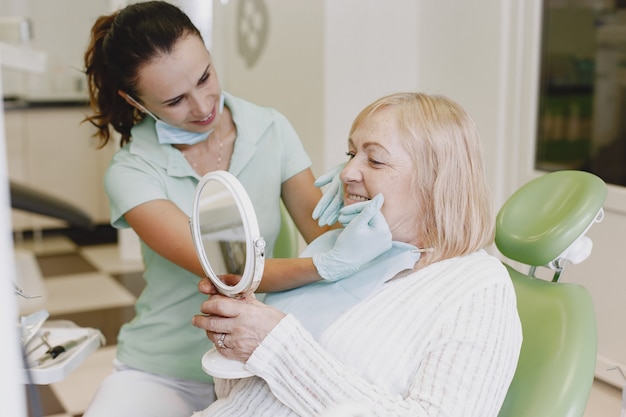 Старшая женщина, имеющая стоматологическое лечение в кабинете стоматолога. Женщина лечится от зубов