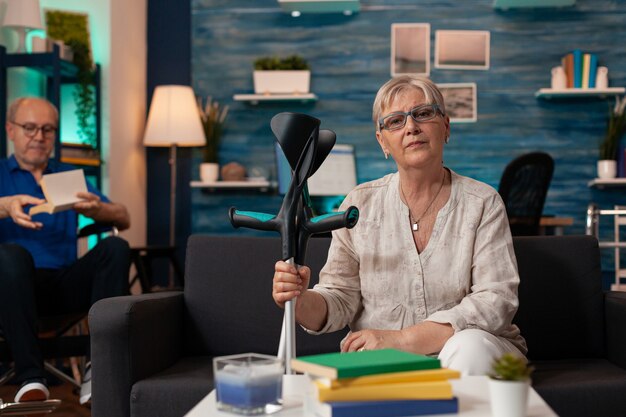 Senior woman holding crutches and looking at camera