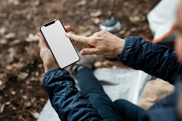 Donna anziana che tiene smartphone con schermo bianco