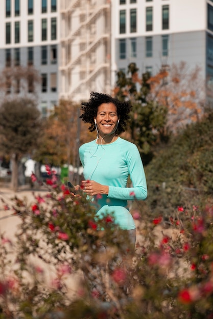 Senior woman jogging outdoors with smartphone and earphones