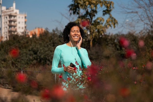 Donna anziana che fa jogging all'aperto con smartphone e auricolari