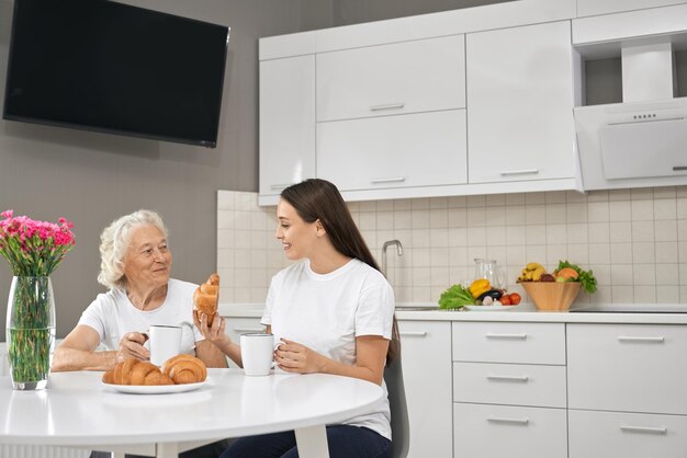 キッチンで孫娘と笑う年配の女性