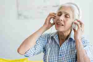 Free photo senior woman listening music on headphone