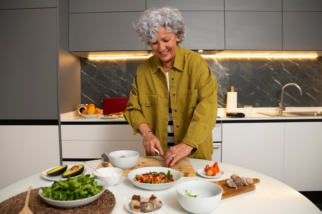 Бесплатное фото Пожилая женщина готовит блюдо с инжиром на кухне