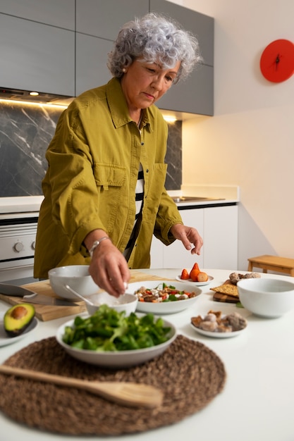 Senior woman making dish with figs in the kitchen
