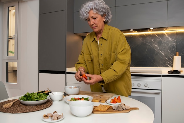 Senior woman making dish with figs in the kitchen