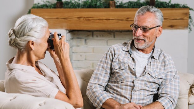 Senior woman photographing her smiling husband with camera