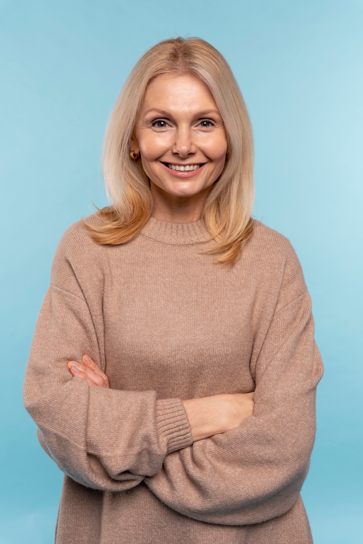 Free Photo senior woman posing and smiling against a blue background