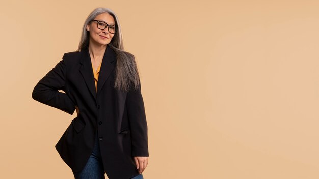 Senior woman posing and wearing glasses against a yellow background