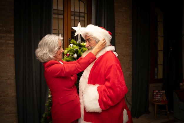 Free photo senior woman setting up man as santa claus