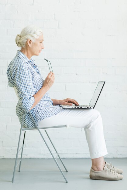Senior woman sitting on chair using laptop