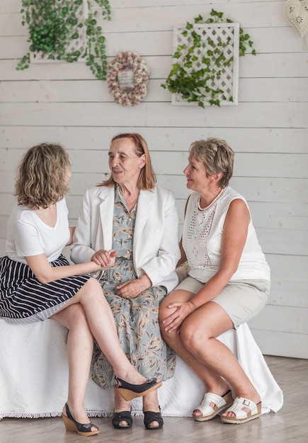 Free photo senior woman sitting on sofa with her daughter and grand daughter at home