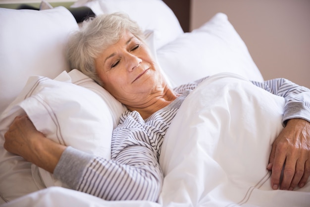 Free photo senior woman sleeping in the big bed