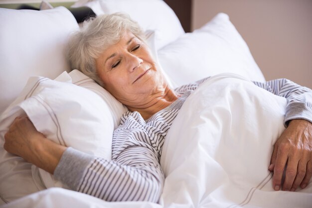 Senior woman sleeping in the big bed
