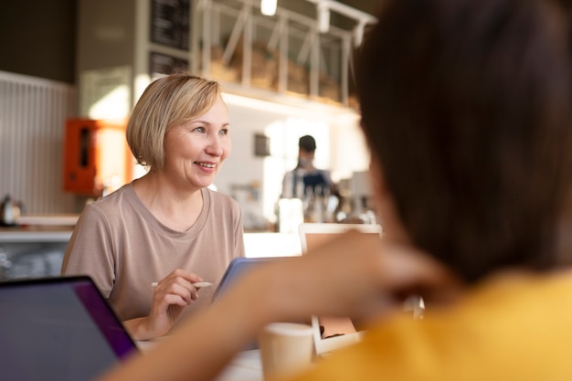 Senior woman spending time with friends and working at a cafe