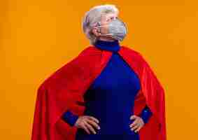 Free photo senior woman superhero wearing red cape and facial protective mask looking aside