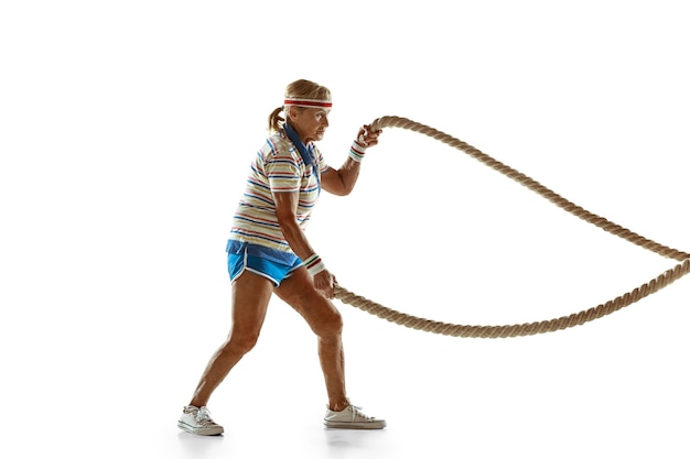 Free photo senior woman training with ropes in sportwear on white wall