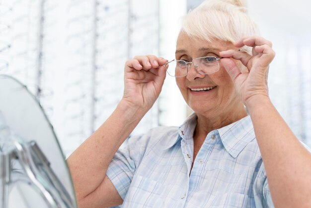 新しい眼鏡をかけようとしている年配の女性