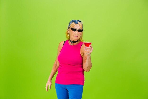 Senior woman in ultra trendy attire isolated on bright green background