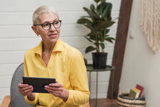 Senior woman using a tablet while looking away