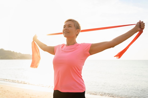 Senior  woman with elastic rope on the beach