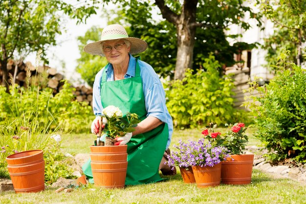 庭に花を持つ年配の女性