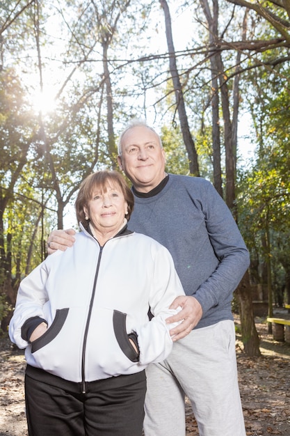 Senior woman with hands in pockets posing with her husband