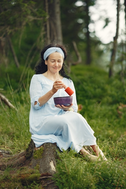 Senior woman with hindu things. Lady in a blue dress. Brunette sitting.