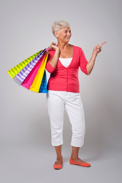 Senior woman with shopping bags showing on copy space