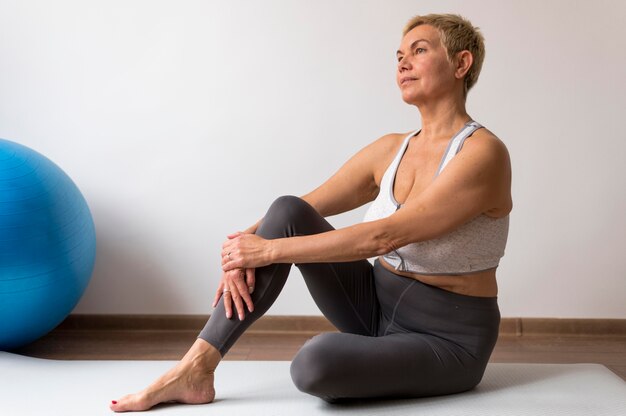 Senior woman with short hair doing stretching exercises