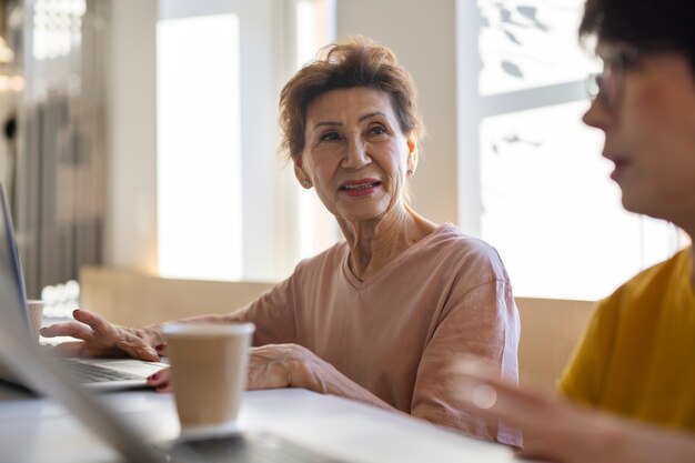 Senior woman working on her laptop and spending time with friends