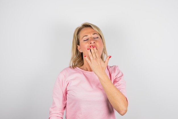 Senior woman yawning in pink blouse