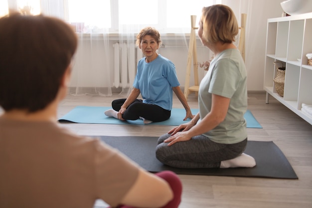 Senior women doing exercises together at home and talking