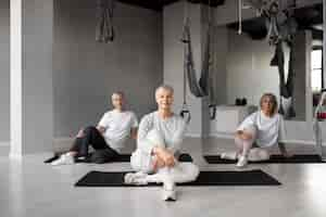 Foto gratuita donne anziane che fanno esercizi di fitness in palestra su stuoie di yoga