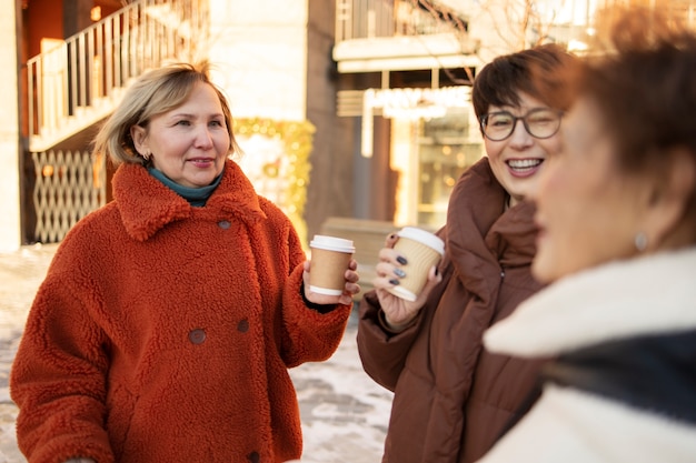 屋外でコーヒーを飲みながら話している年配の女性 Premium写真