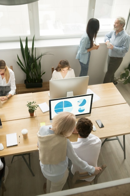 Senior and young employees working in office, top vertical view