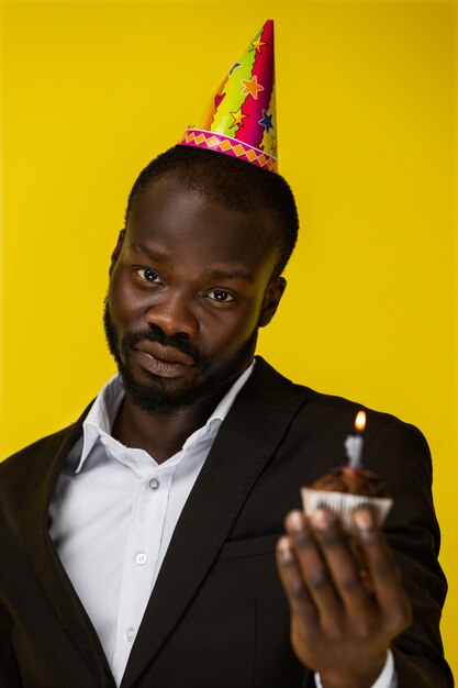 Sensitive handsome African man holding a birthday cake.