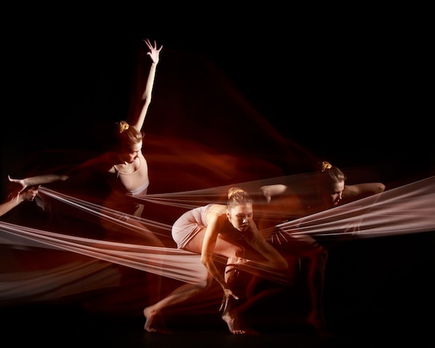 The sensual and emotional dance of beautiful ballerina with white fabric