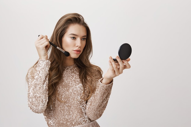 官能的な女性の鏡は化粧を適用します
