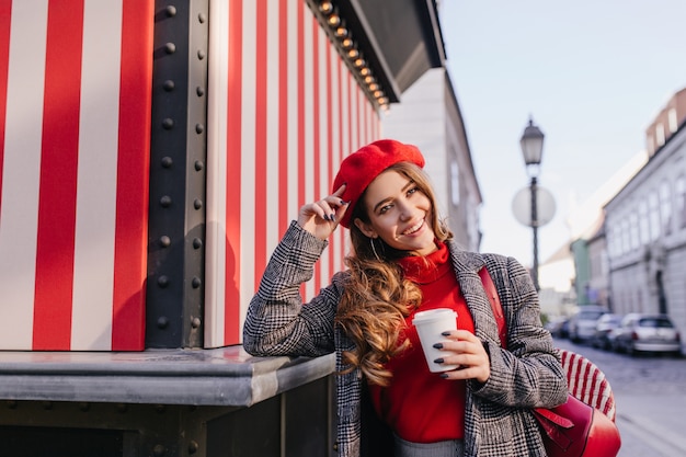 Sensual french girl with black manicure enjoying photoshoot on avenue in autumn morning