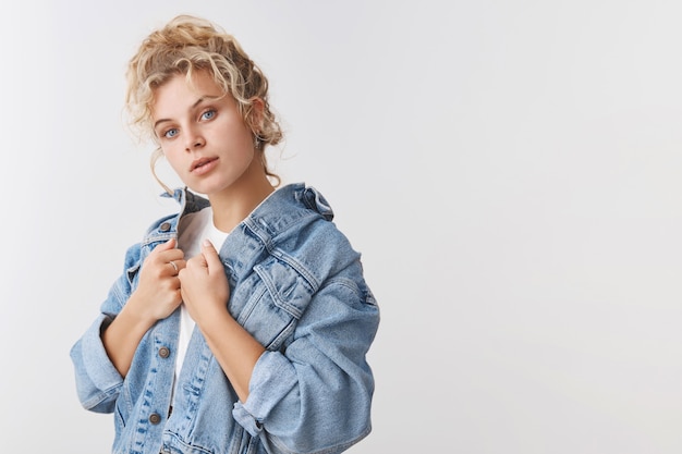 Sensual good-looking millennial blond curly-haired woman blue eyes tilt head check denim jacket look camera posing mirror choose outfit pool party, look confident have fashion taste, white wall