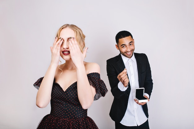 Free photo sensual lovely moments of young woman in luxury dress with closed eyes waiting for surprise from handsome man with ring. celebrating valentines day, lovers, gift.