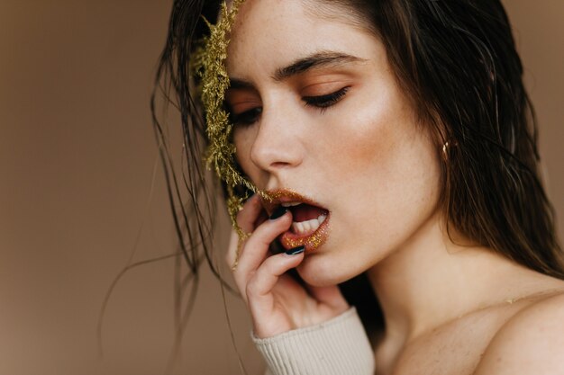 Sensual pale girl posing . Close-up shot of lady isolated on brown wall.