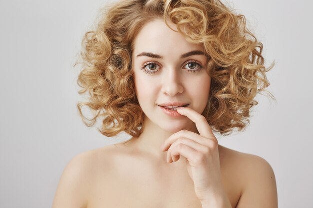Sensual pretty female with curly hair and naked shoulders, looking tempting