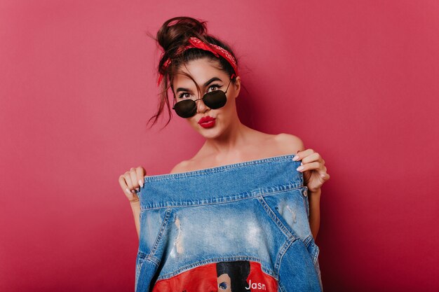 Sensual tanned female model holding blue denim jacket 