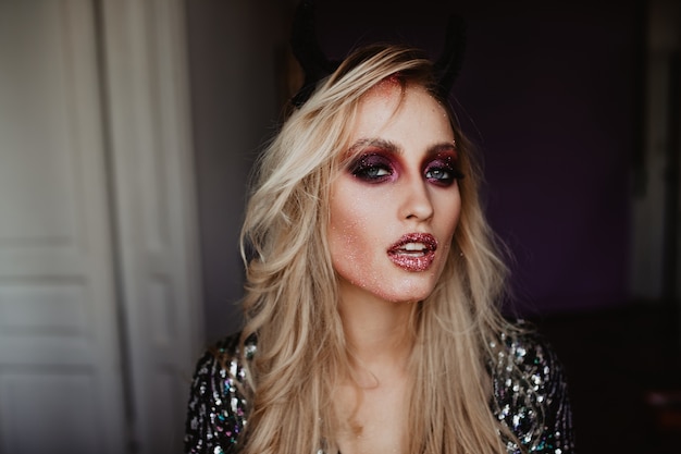 Sensual white lady with shiny purple eyeshadows. serious blonde woman with dark makeup.