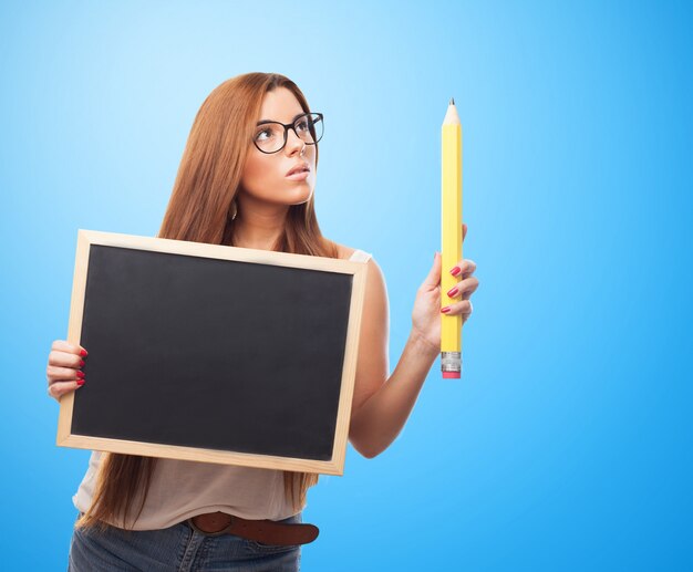 Sensual woman holding blackboard and big pencil